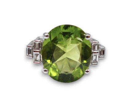 a close up of a ring with a green stone surrounded by diamonds