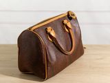 a brown leather handbag sitting on top of a wooden table