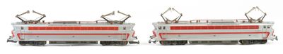two model trains sitting side by side on a white surface