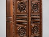 une vieille armoire en bois avec des sculptures et des gravures sur les portes