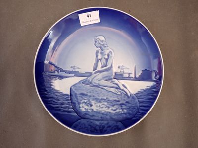 a plate with a picture of a mermaid sitting on a rock