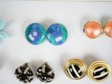 several pairs of earrings are displayed on a white surface
