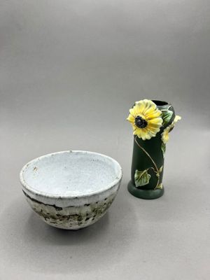 a small bowl and a vase with a flower in it