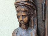 a wooden statue of a woman with a hat on her head