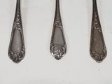 four spoons and a fork are lined up on a white surface