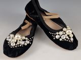 une paire de chaussures en velours noir ornées de perles et de nœuds