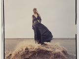an old photo of a woman in a long dress standing on top of a pile of sand