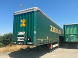 two green semi trailers parked next to each other in a parking lot