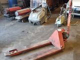 un petit camion garé dans un garage, à côté d'un chariot élévateur