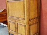 a tall wooden cabinet with drawers in the corner of a room