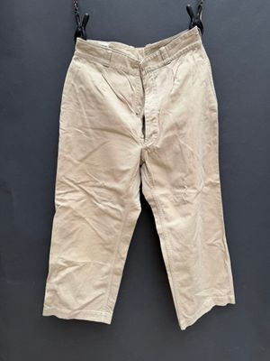 un vieux pantalon beige accroché à un mur noir
