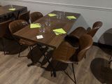 Des tables et des chaises sont alignées dans une pièce, avec un mur en arrière-plan.