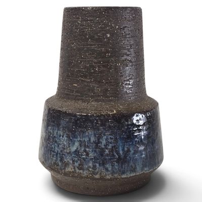 un vase bleu et noir posé sur une surface blanche