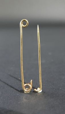 une paire d'épingles de sûreté plaquées or sur un fond noir