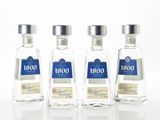 trois bouteilles d'alcool sont alignées sur une surface blanche