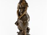 a bronze statue of a woman sitting on a rock