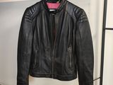 une veste en cuir noir suspendue à un porte-manteau dans une pièce