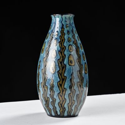 a blue and brown vase sitting on a white table