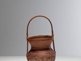 small woven basket with handle on a white surface
