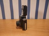 a small camera sitting on a wooden table with a blue and white striped wall behind it