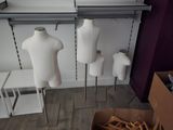 plusieurs mannequins dans une pièce remplie d'une grande variété de vêtements