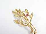 une broche en or ornée de feuilles et d'une pierre rouge