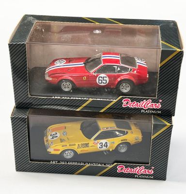 deux petites voitures posées dans une boîte sur une surface blanche