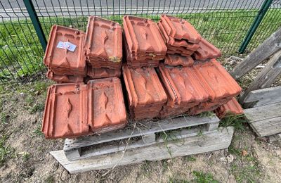 un tas de briques posé sur une palette devant une clôture