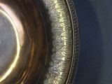 a silver plate with a gold rim on a blue table