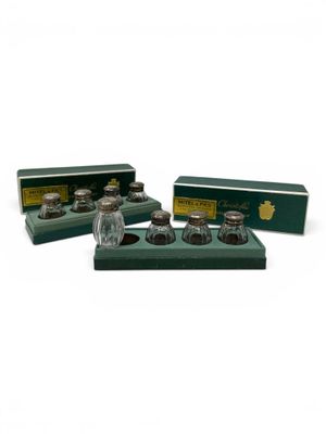 a set of three glass salt and pepper shakers in a green box
