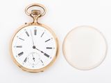a gold pocket watch sitting next to a glass of water