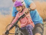 a man riding a bike with a little girl on it