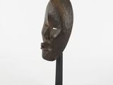 an image of a wooden mask on a black stand on a white background