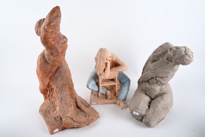 three clay sculptures of people sitting on a chair