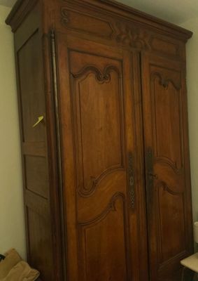a wooden armoire in the corner of a room