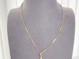 un collier avec une croix en or, présenté sur un mannequin devant une vitrine