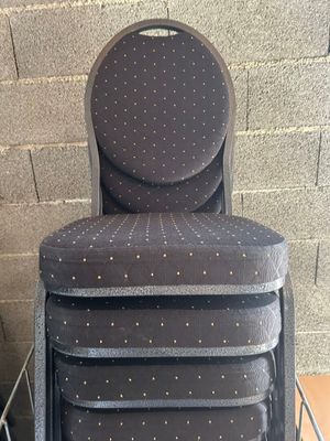 une pile de quatre chaises posée contre un mur de briques