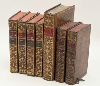 plusieurs vieux livres posés les uns sur les autres sur une surface blanche