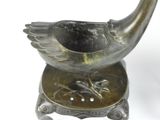 a bronze bird that is sitting on top of a stand