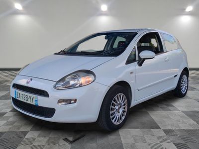 la petite voiture blanche est garée sur un sol en damier