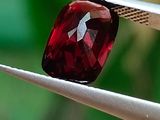 un gros plan d'une pierre rouge tenue par une pince