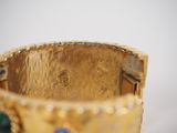 a close up of a gold bracelet with blue and green stones