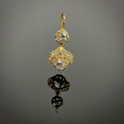 a close up of a gold and diamond pendant on a reflective surface