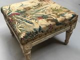 un tabouret ancien dont l'assise est recouverte d'un tissu à motifs floraux