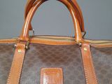 brown and tan handbag with brown leather handles on a table