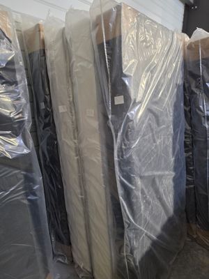 many mattresses wrapped up in plastic in a warehouse