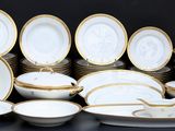 de nombreuses assiettes et bols blancs et dorés sur la table