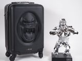 une statue en argent représentant un gorille, à côté d'une valise noire