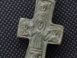 a close up of a silver cross on a black surface