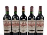 four bottles of red wine are lined up on a white surface